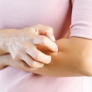 midsection of woman scratching hand against white background