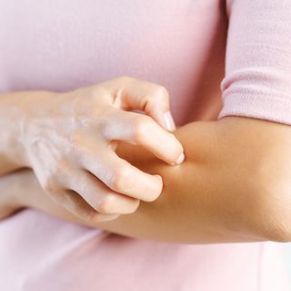 midsection of woman scratching hand against white background