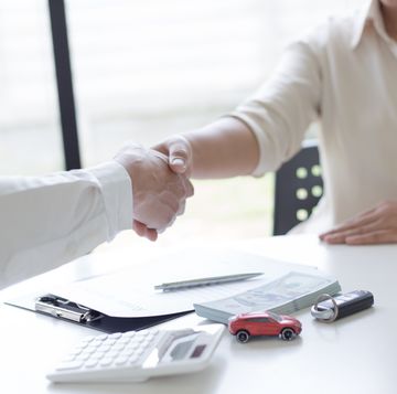 midsection of woman shaking hand with car insurance agent at office