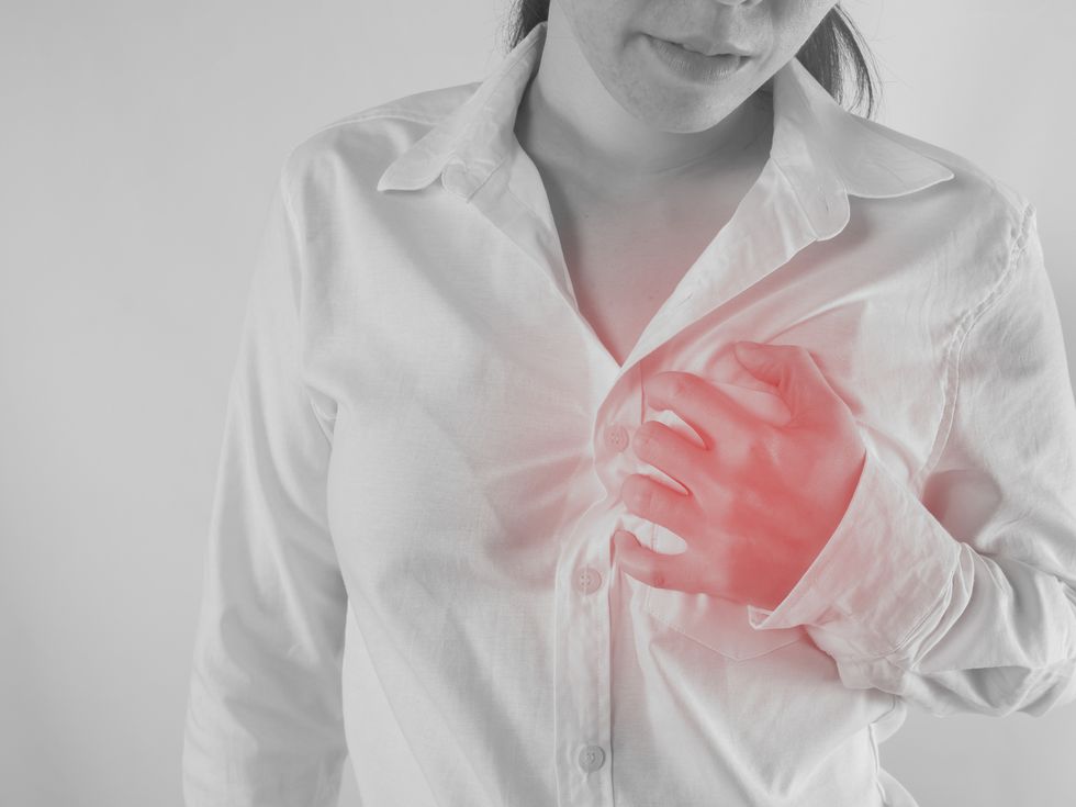 midsection of woman suffering from chest pain against white background