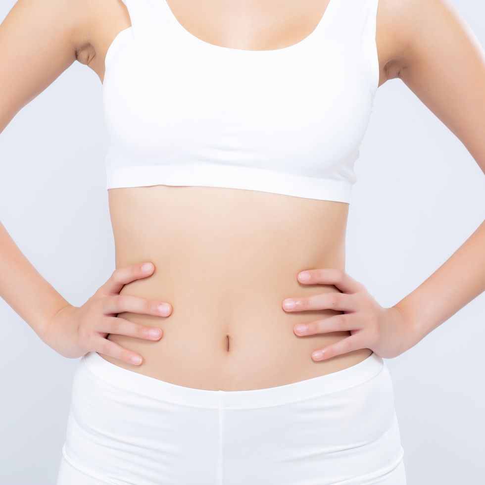 midsection of woman with arms akimbo standing against white background