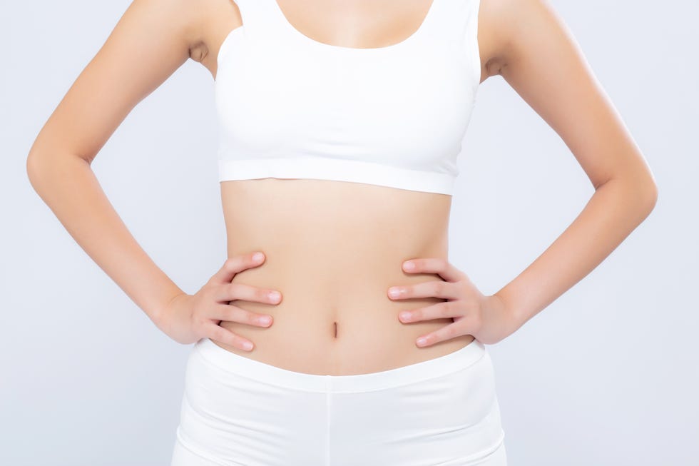 midsection of woman with arms akimbo standing against white background