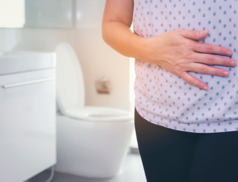 midsection of woman with stomachache standing in bathroom