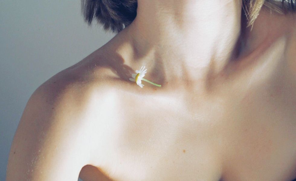 midsection of woman with white flower on clavicle