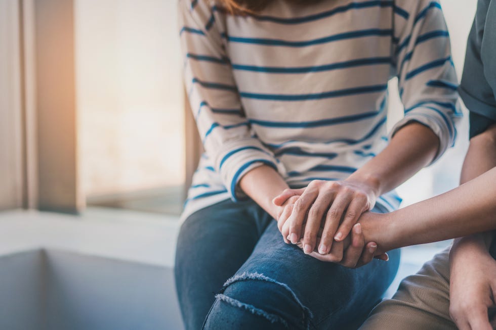 midsection of women consoling friend while sitting at home