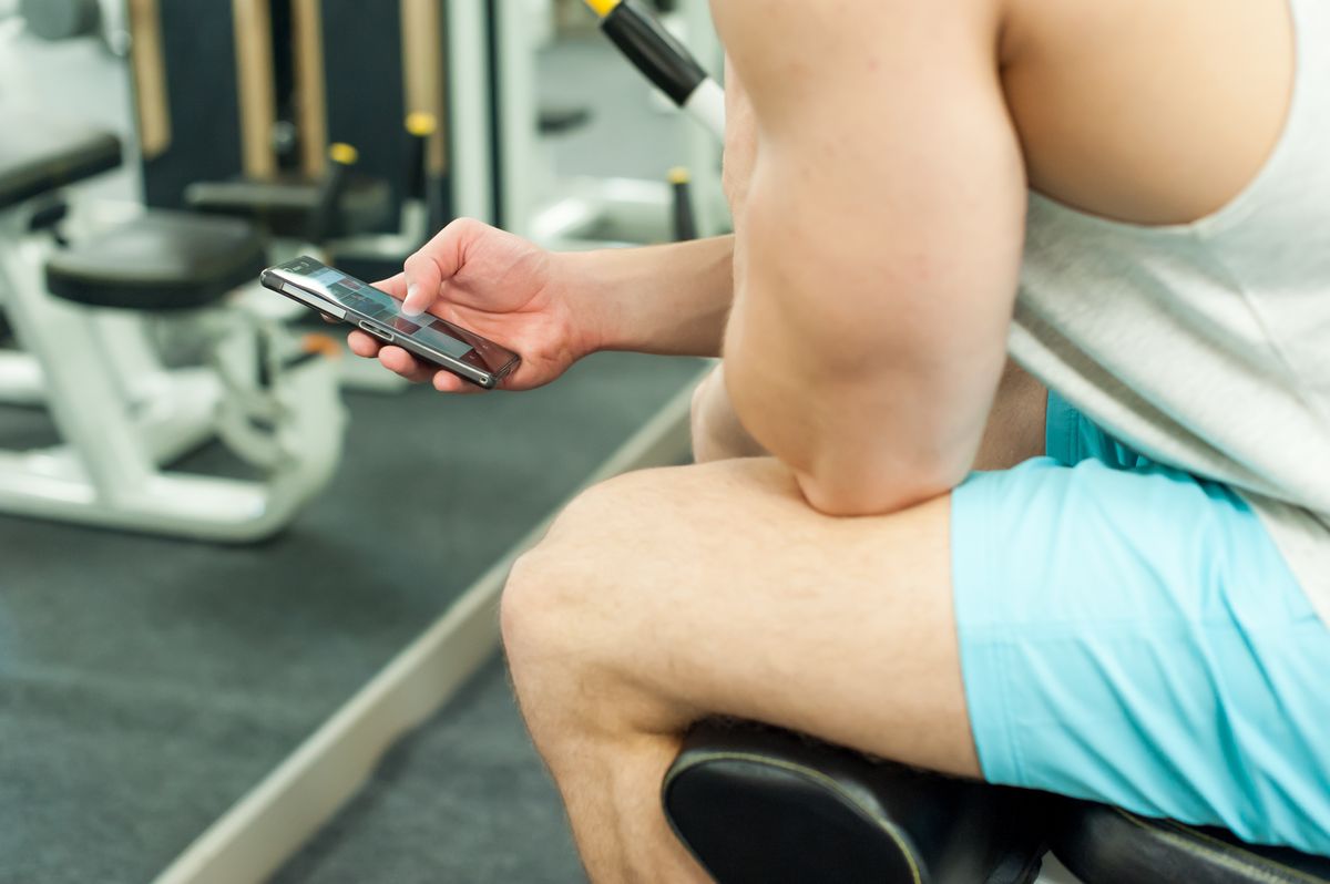 Midsection Of Young Man Using Phone While Sitting At Gym