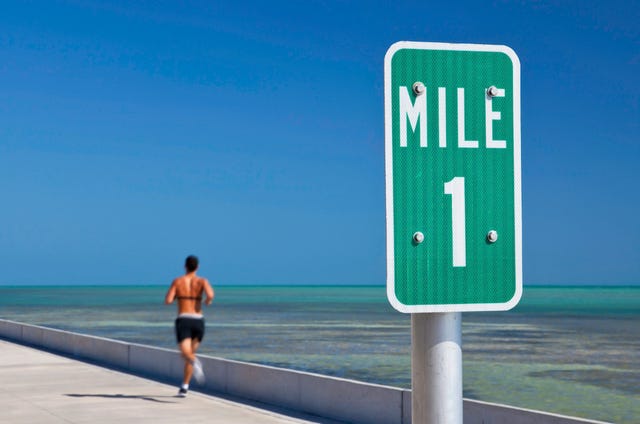 mile one sign and a man running in key west