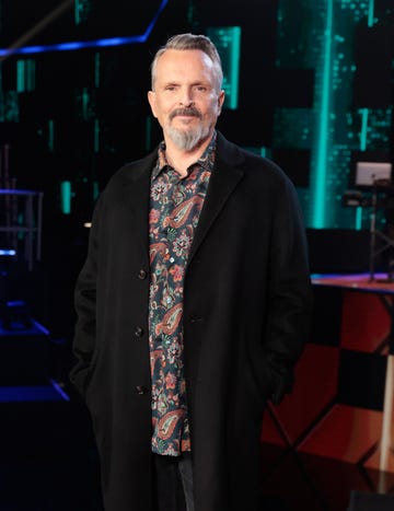 el cantante con abrigo negro y camisa estampada