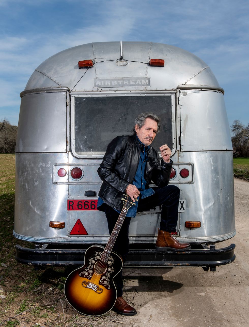 miguel rïos posa con una guitarra frente a una caravana