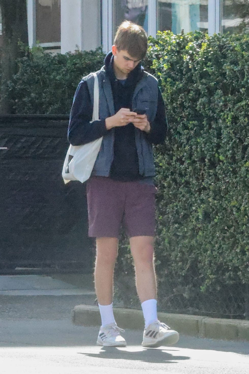 el hijo de la infanta cristina con ropa deportiva mirando el movil