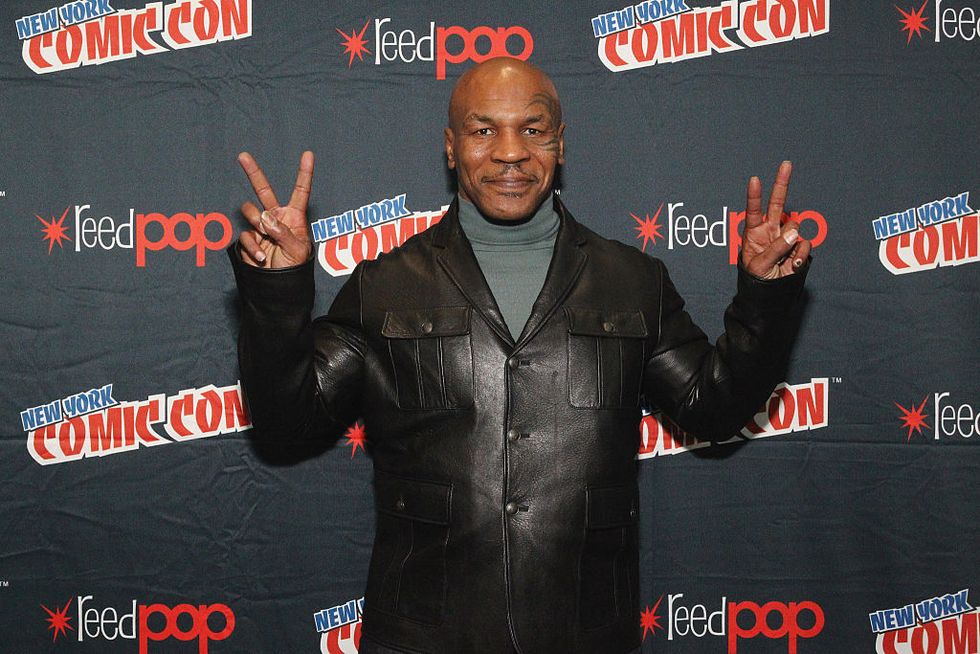 mike tyson giving double peace signs with his hands at a comic convention