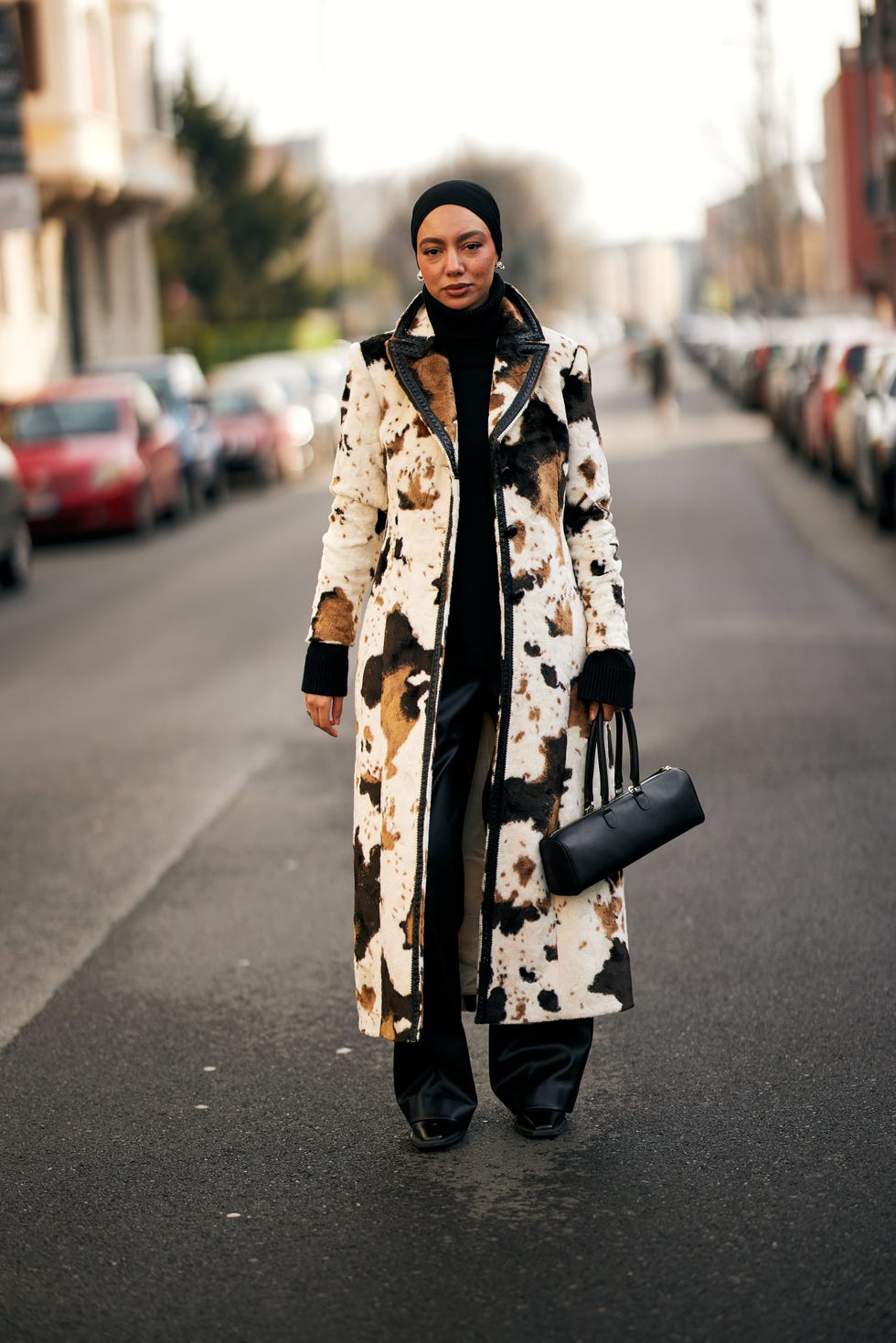 person wearing a long coat with a bold pattern in a city setting