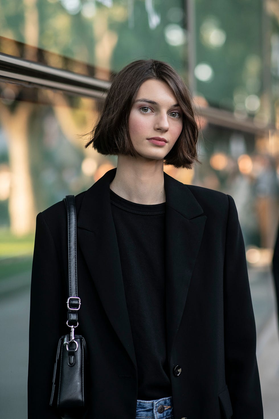fashionable person wearing a black blazer and tshirt with denim jeans best brunette bob haircut for summer