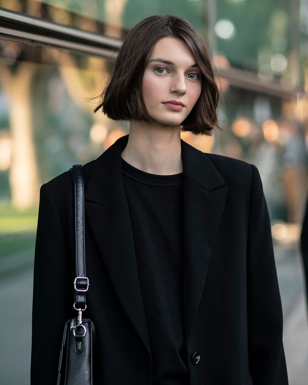 fashionable person wearing a black blazer and tshirt with denim jeans best brunette bob haircut for summer
