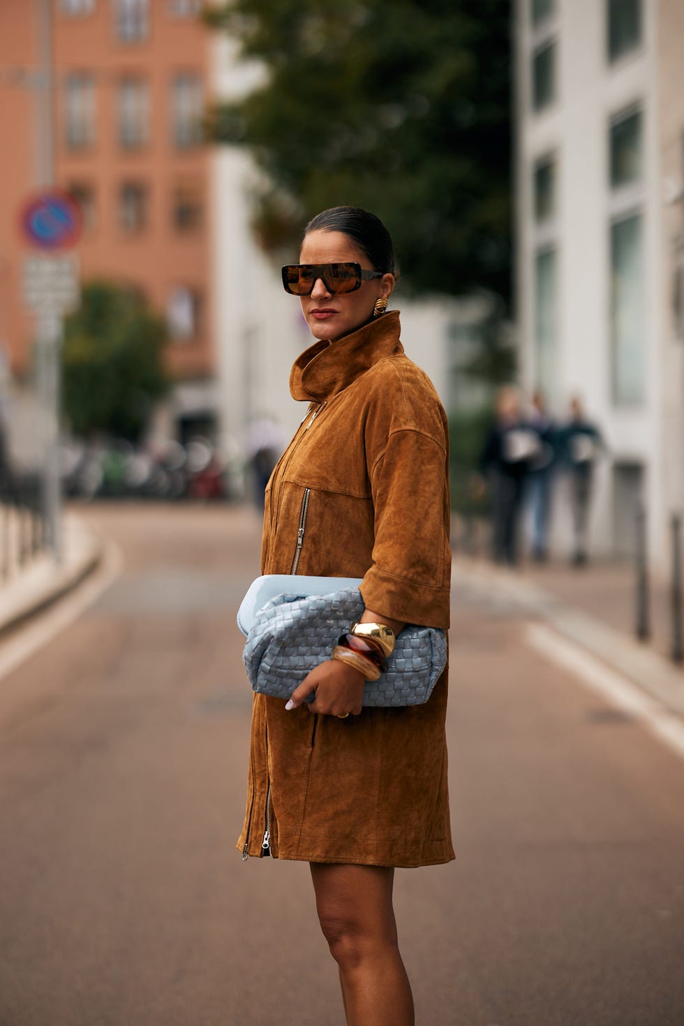woman in a brown suede coat holding a blue handbag