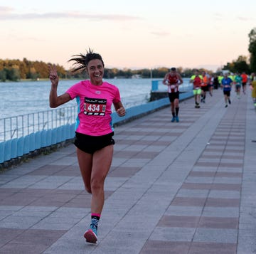 runner in a pink shirt participating in a race alongside a body of water runner in a pink shirt participating in a race alongside a body of water