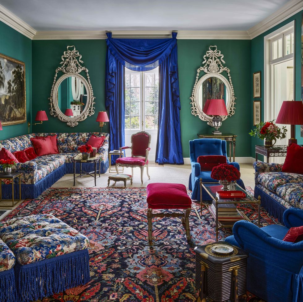 a living room with green walls and floral furniture and blue curtains with red accents all over