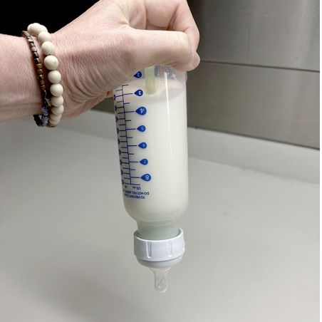 a staff member of the good housekeeping institute holds a baby bottle upside down to check for leaks, part of a story on the best baby bottles