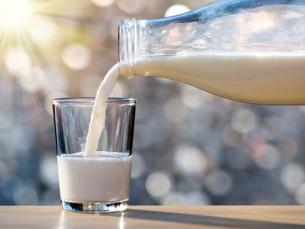 milk bottle filling a glass for breakfast lit by sunlight