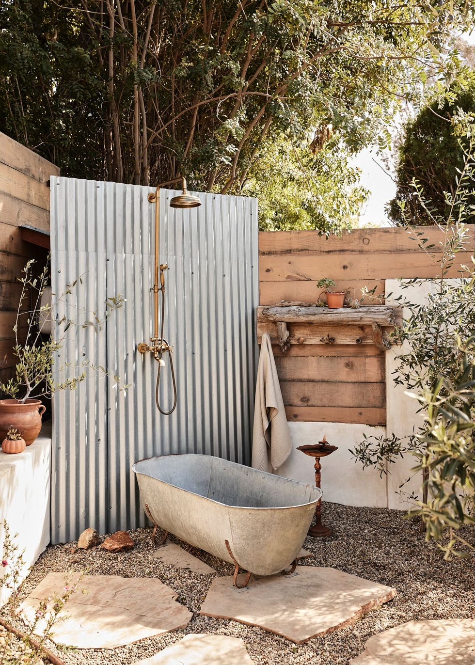 a outdoor bathtub and shower against corrugated metal