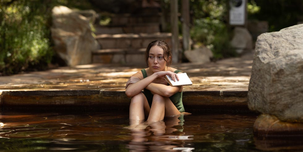 Individual sitting in a water pool with a book