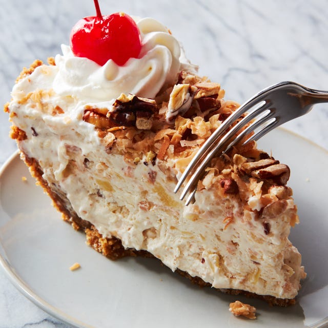 layered pie topped with crushed nuts, whipped cream, and cherries