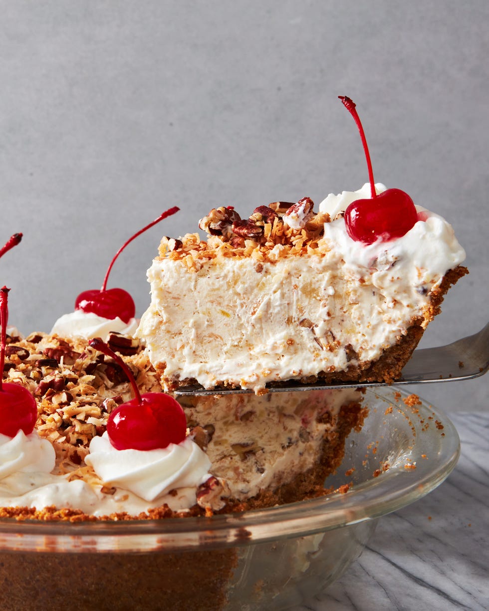 layered pie topped with crushed nuts, whipped cream, and cherries