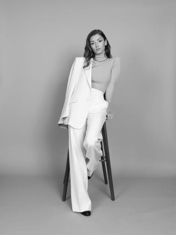 a seated figure wearing stylish clothing in a monochrome setting