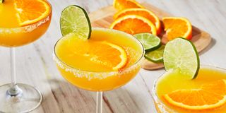 mimosa margaritas with sugared rims garnished with lime wheels