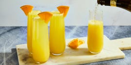 orange juice and champagne in a flute garnished with an orange wedge