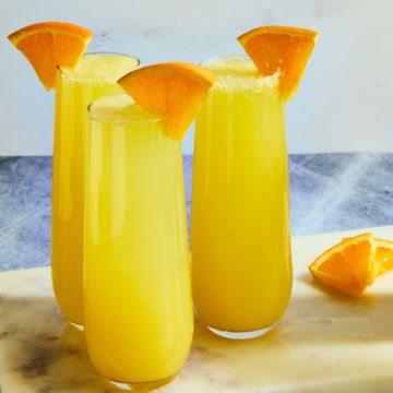orange juice and champagne in a flute garnished with an orange wedge