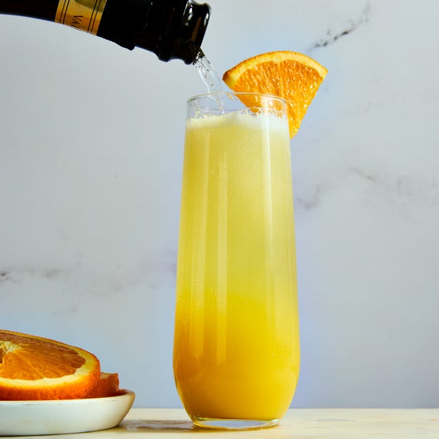 orange juice and champagne in a flute garnished with an orange wedge