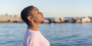 vrouw doet buiten bij de zee aan mindfulness door ademhalingsoefeningen