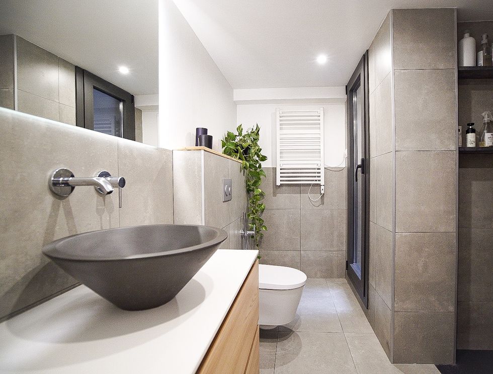 baño de diseño moderno e industrial con mueble de lavabo de madera y paredes y suelo efecto microcemento
