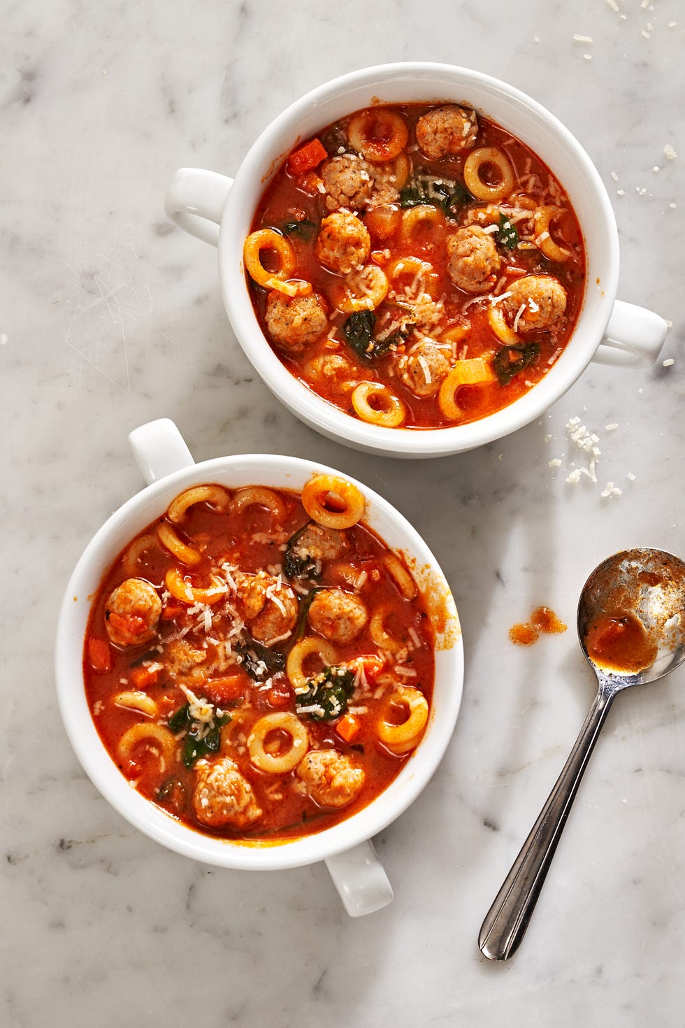 mini meatballs and anelletti ring shaped pasta sit inside two bowls of marinara soup