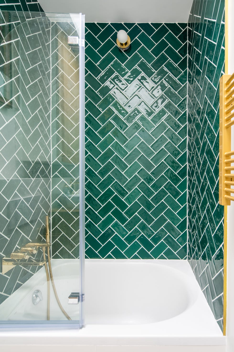 Pequeña bañera con azulejos verdes en las paredes