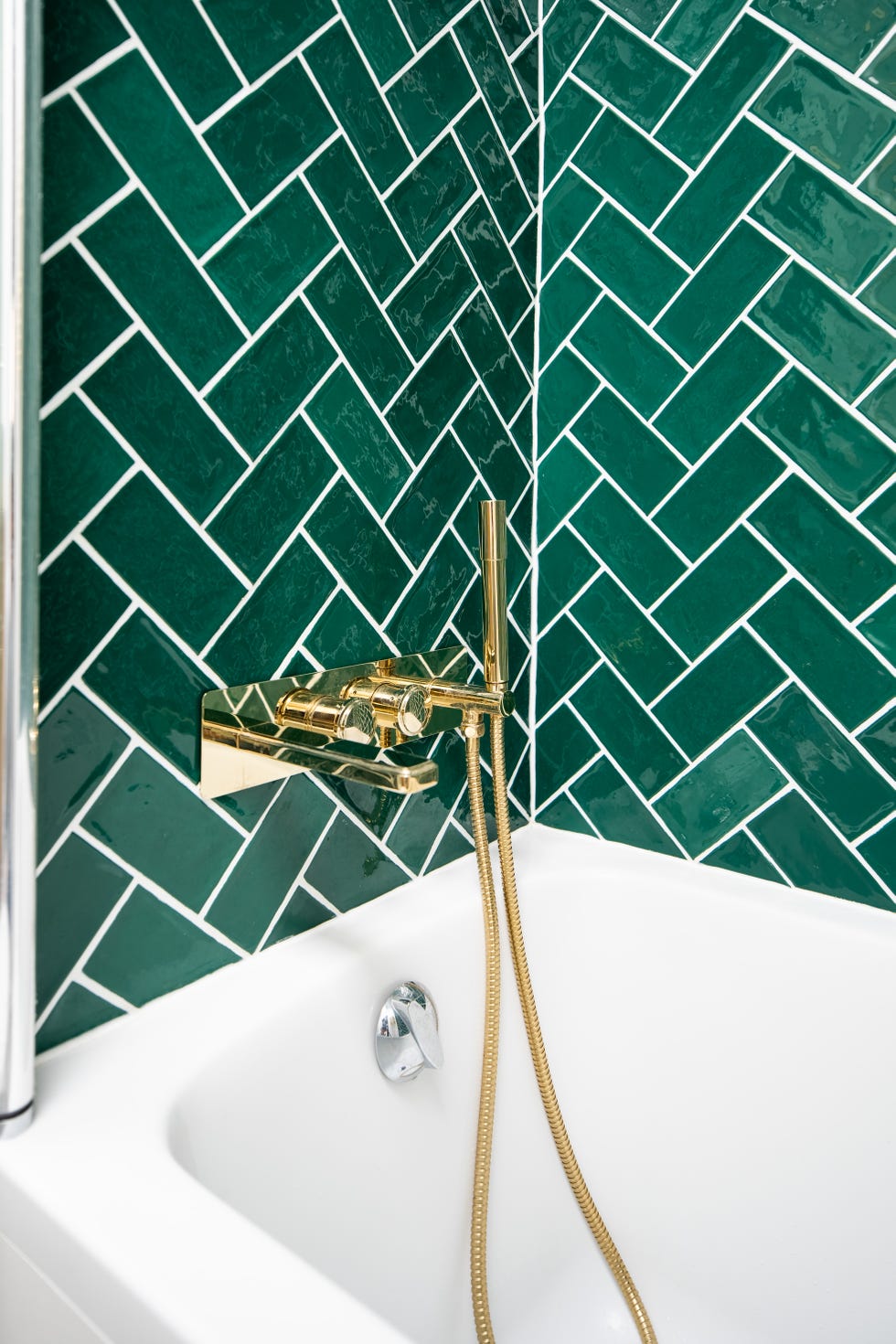 Pequeña bañera con azulejos verdes en las paredes