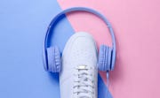 minimalism music lover  headphones, white sneakers on blue pink pastel background top view flat lay