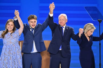 tim walz and his family raise their arms at the democratic national convention