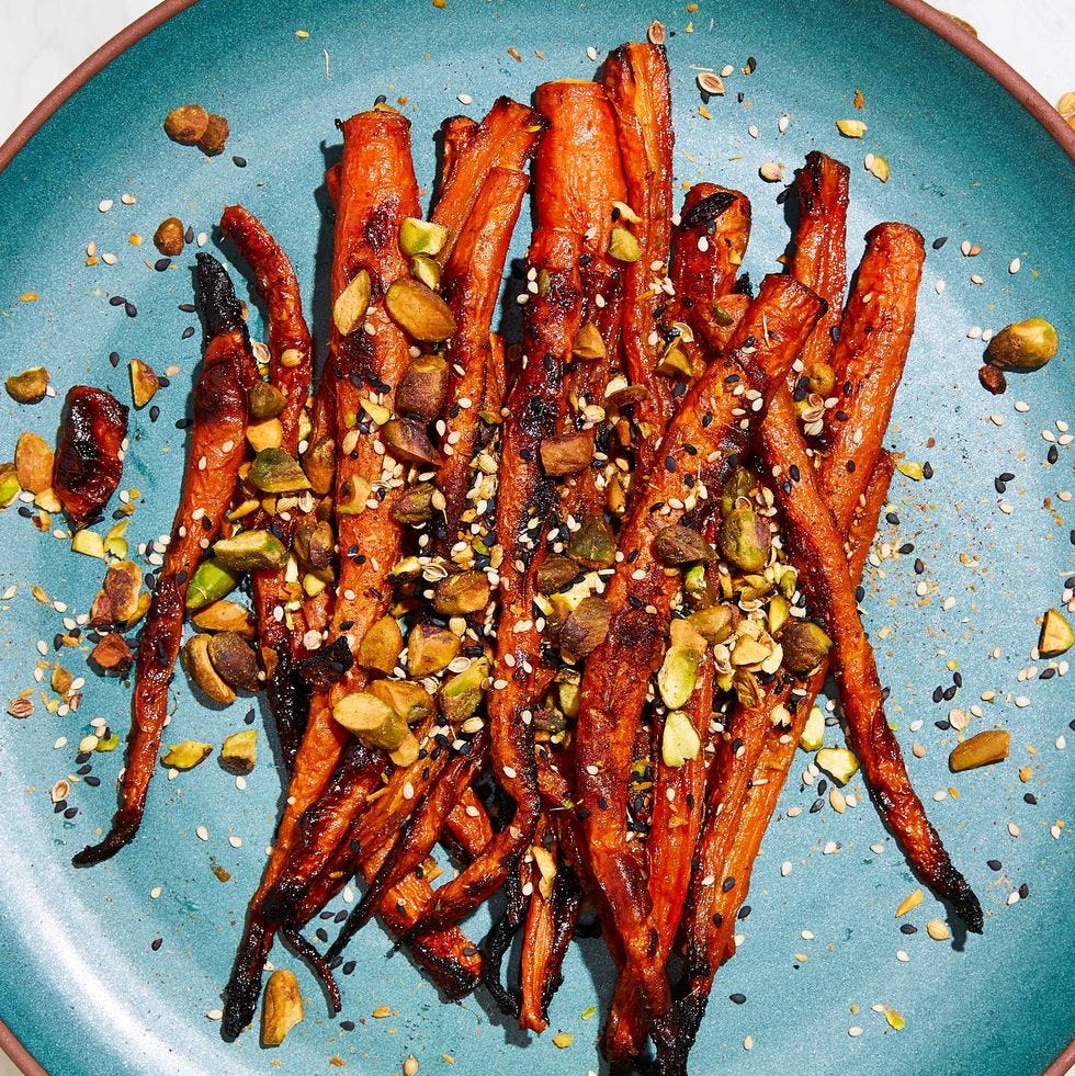 maple roasted carrots topped with black and white sesame seeds and pistachios on a teal plate