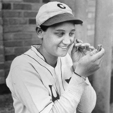 woman in a baseball uniform applying makeup