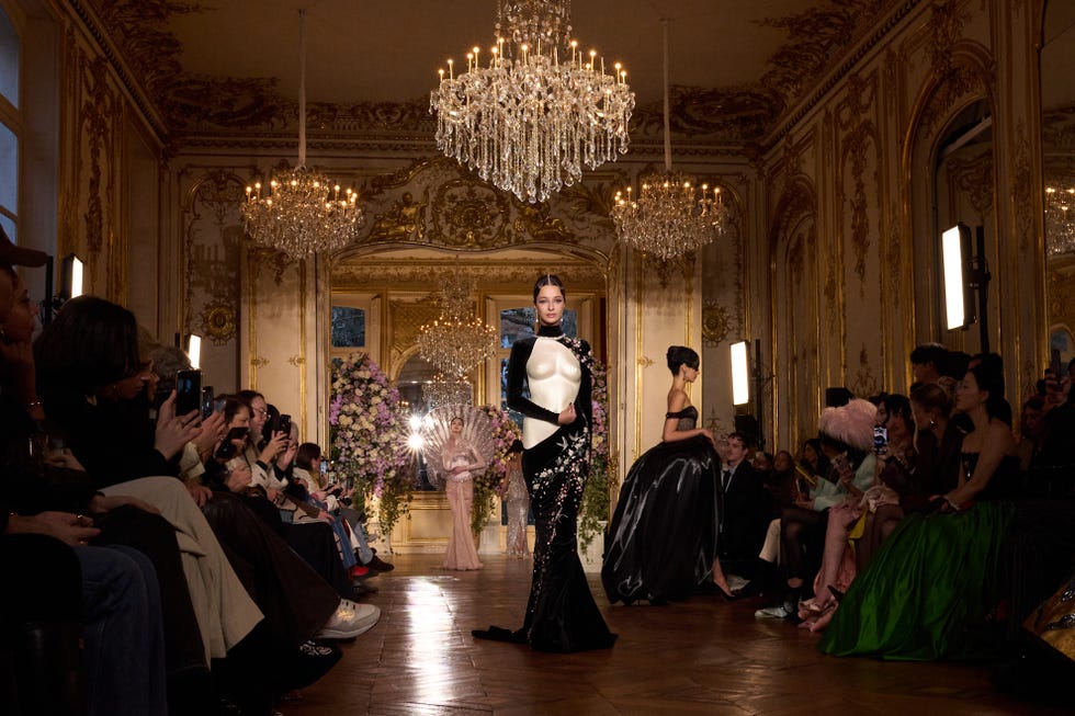 Runway scene featuring models showcasing high fashion clothing in an ornate setting