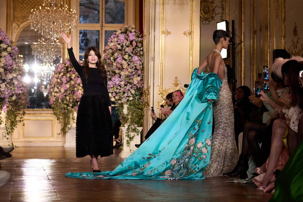 A fashion show scene with a model and a stylist on the runway