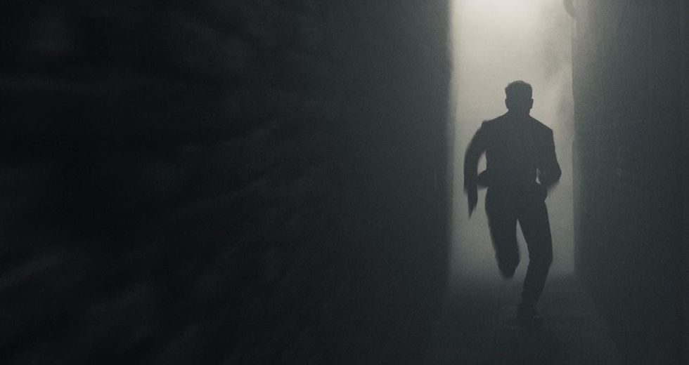 tom cruise runs down a dark and smoky environment in mission impossible 7 still