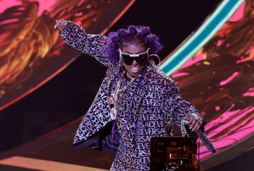 missy elliott holding a microphone while dancing during a stage performance
