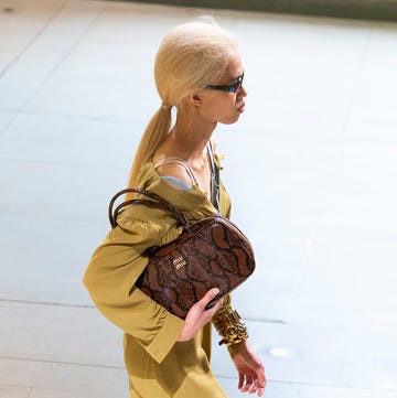 model walking in a stylish outfit carrying a designer handbag model walking in a stylish outfit carrying a designer handbag