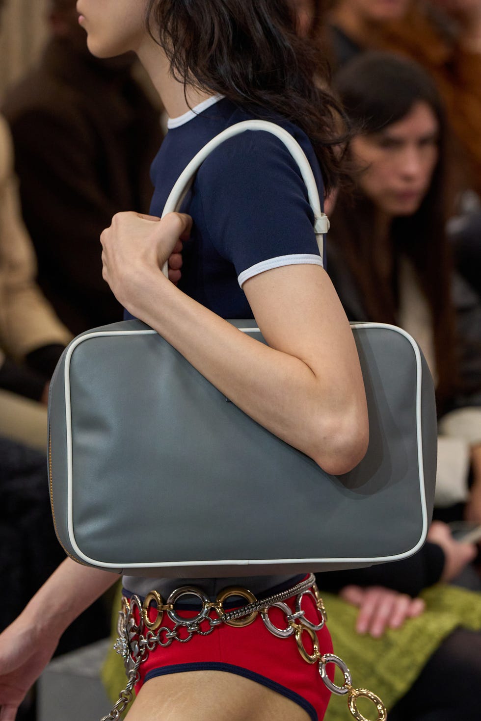 Fashion model carrying a gray handbag during a runway show