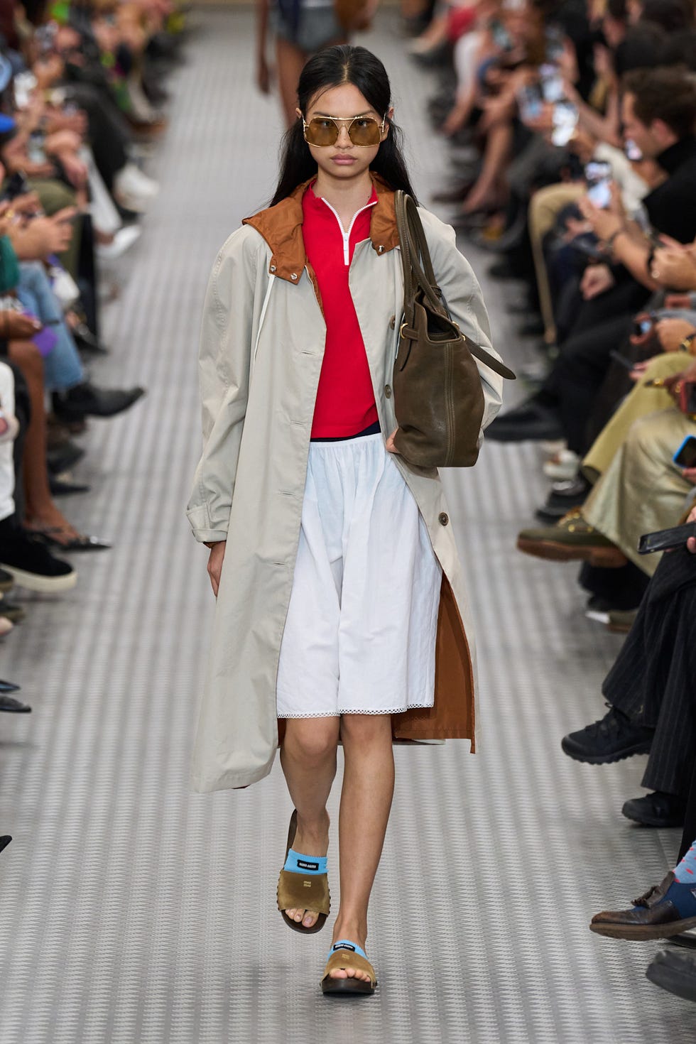A model walks down a runway showcasing a fashion ensemble A model walks down a runway showcasing a fashion ensemble