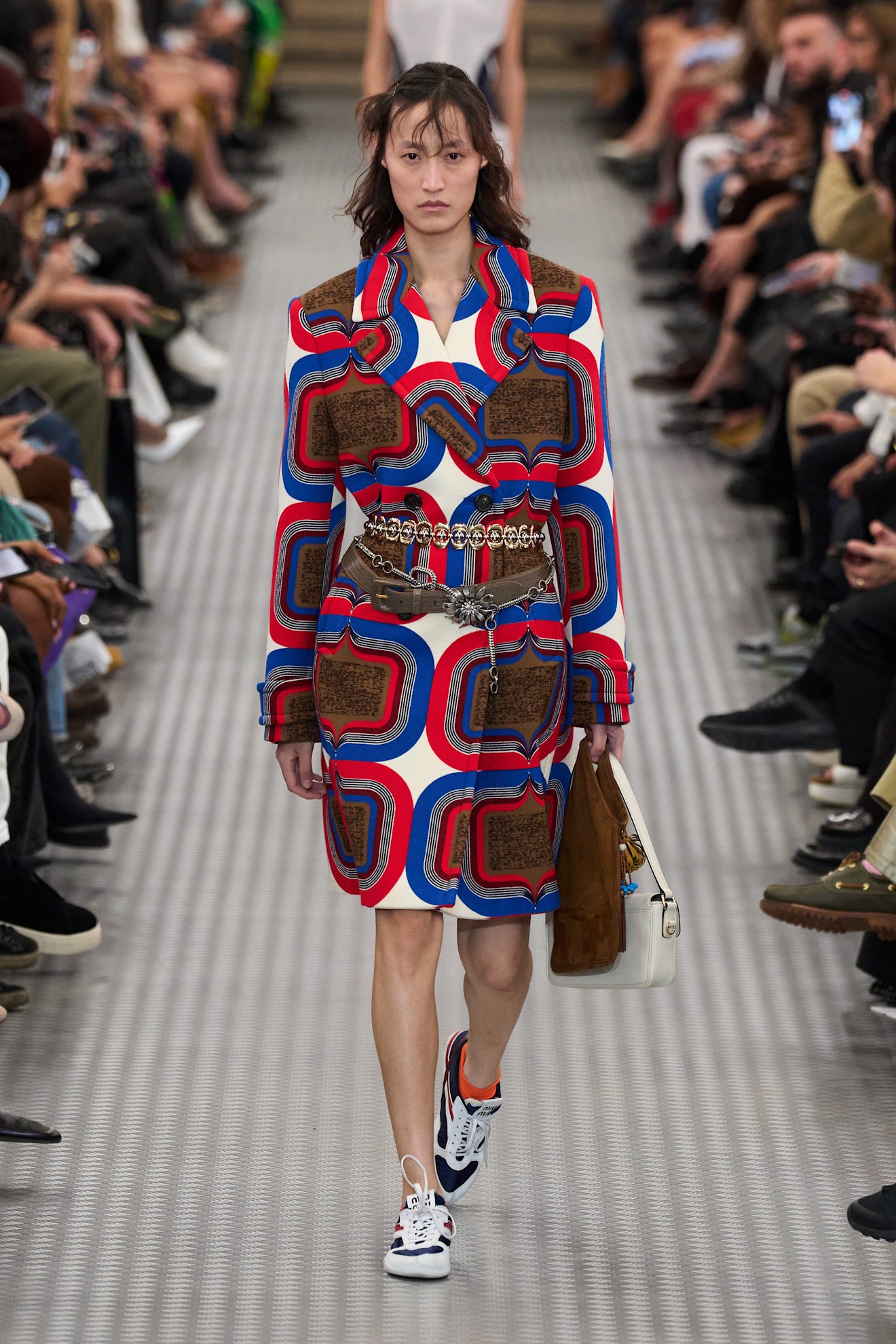Model walking the runway in a vibrant patterned coat dress