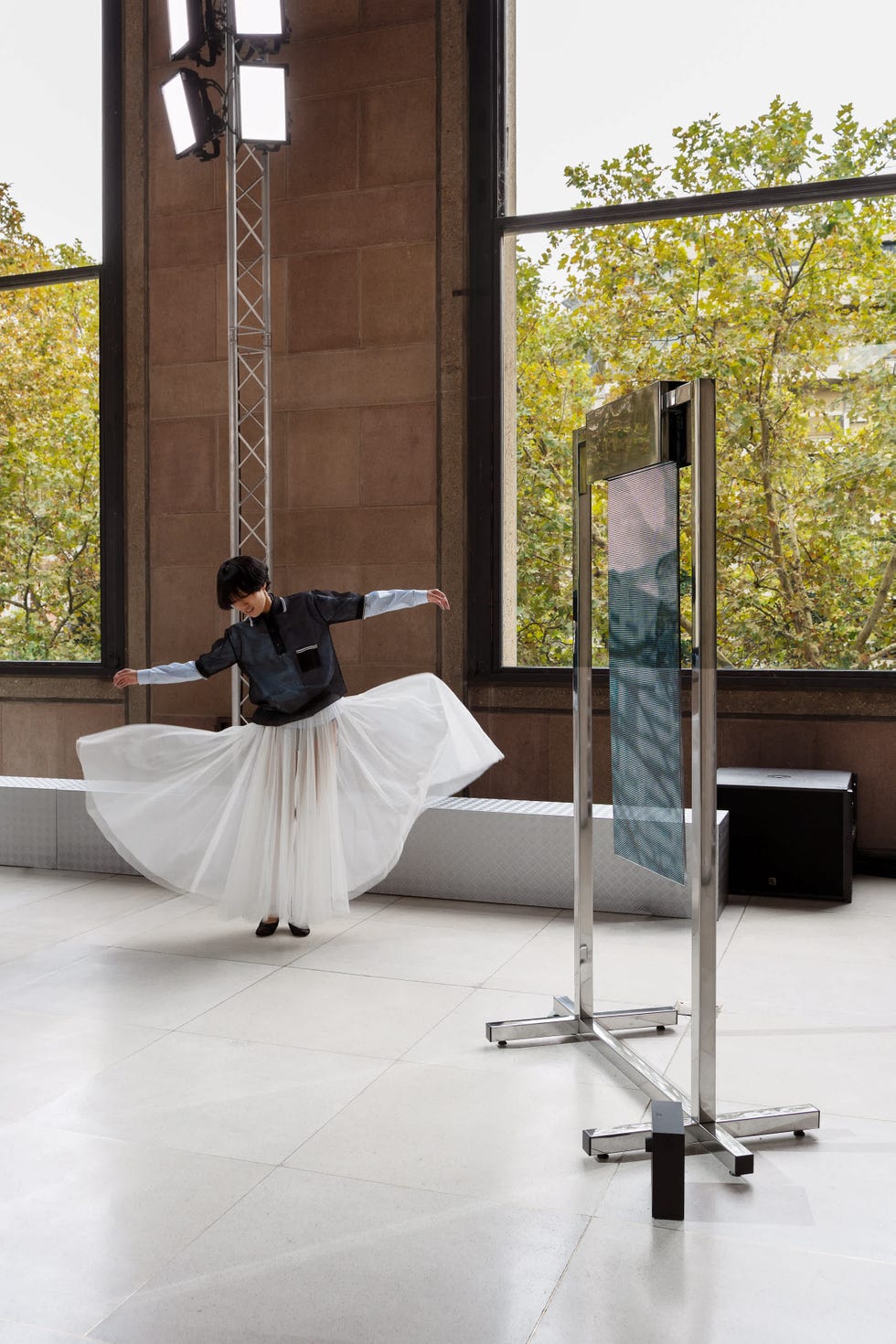 a dancer is captured in motion with one arm raised and the other extended as she twirls in a long flowing white skirt and a dark top